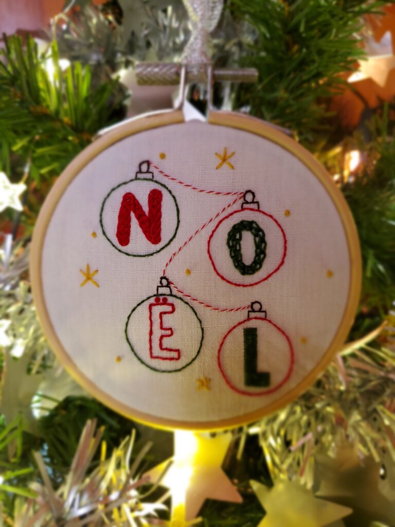 Boule Noël brodée main motif NOËL avec une guirlande reliant chaque boule de Noël et des petites étoiles tout autour