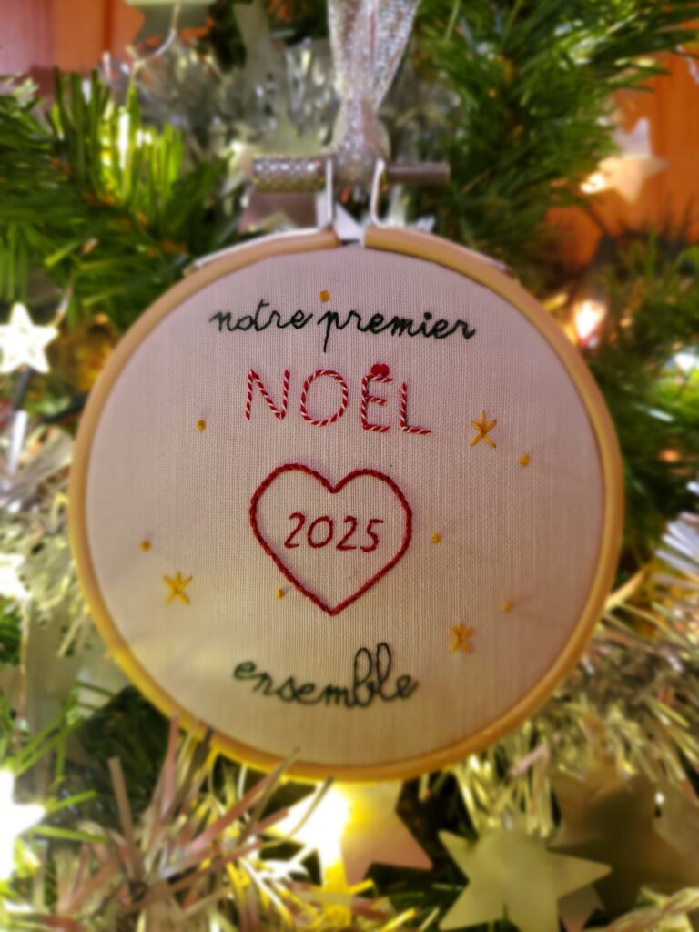 Boule de Noël brodée à la main portant la mention "notre premier Noël ensemble" et la date 2025, avec un coeur central