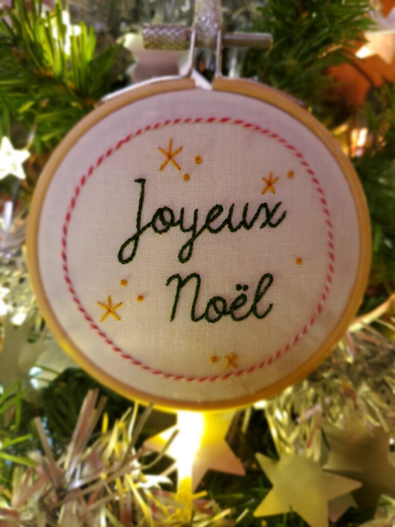 Boule brodée main portant l'inscription "Joyeux Noël"