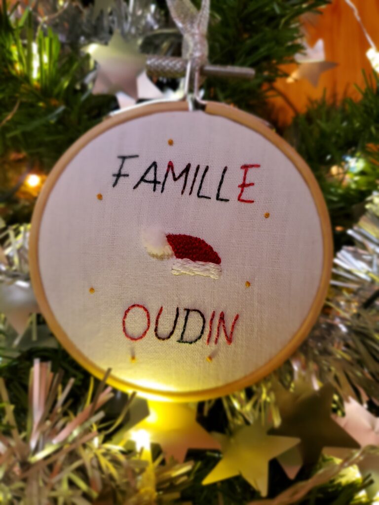 Boule de Noël brodée à la main avec un bonnet de lutin et la mention "Famille" + nom de la famille (capitales / point arrière)