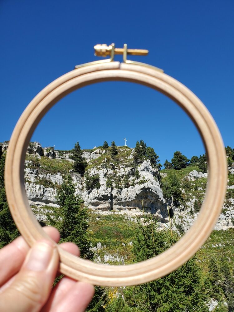 Croix au sommet de l'Aulp du Seuil au loin vue à travers un tambour de broderie